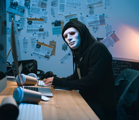 How To avoid Consequences of Ransomware Attack - hacker sitting in front of the computer looking at the camera