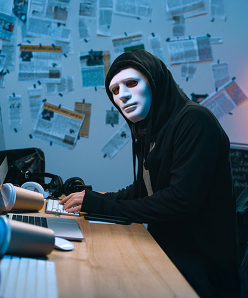 How To avoid Consequences of Ransomware Attack - hacker sitting in front of the computer looking at the camera